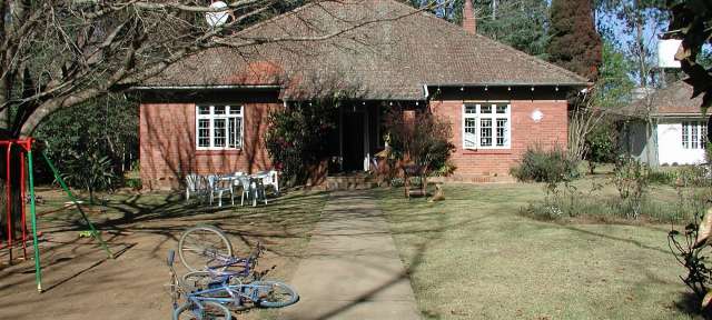 1998: Pfarrhaus mit weißer Garage in Hermannsburg Südafrika Zwei Fahrräder stehen vor einem Backsteinhaus