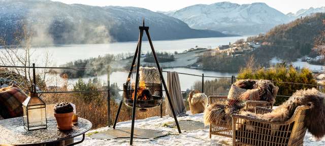 ©TheIngalls 62°NORD Ein Tisch und Stühle im Schnee mit einem Feuer im Hintergrund