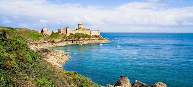 Vielfältige Küste: Cote d'Emeraude am tiefblauen Atlantik Eine Burg sitzt auf einer Klippe über dem Ozean